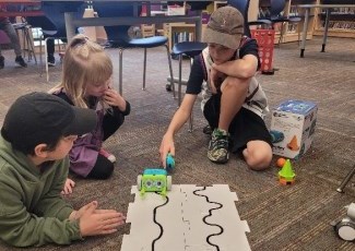 Photo of kids playing with a Botley Robot which were generously donated to the library from the Rosa Rattray Early Literacy Fund. 